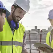 people - 3 people in yellow vests and hard hats reviewing plans