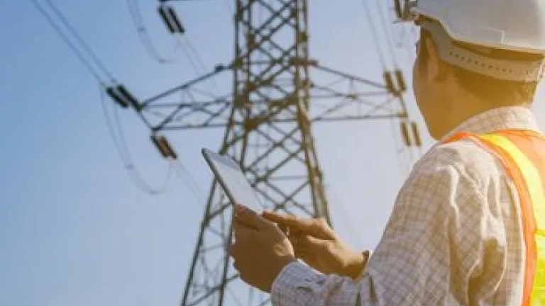 Electrical engineer with tablet inspecting electrical tower