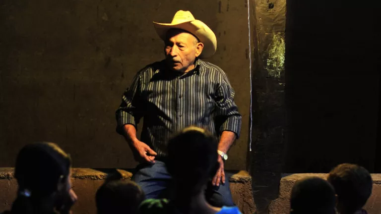 Man talking to a a crowd of children at night.