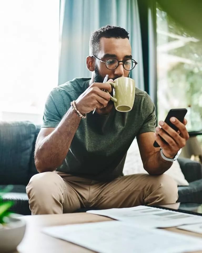 tech - sitting man drinking coffee looking at phone